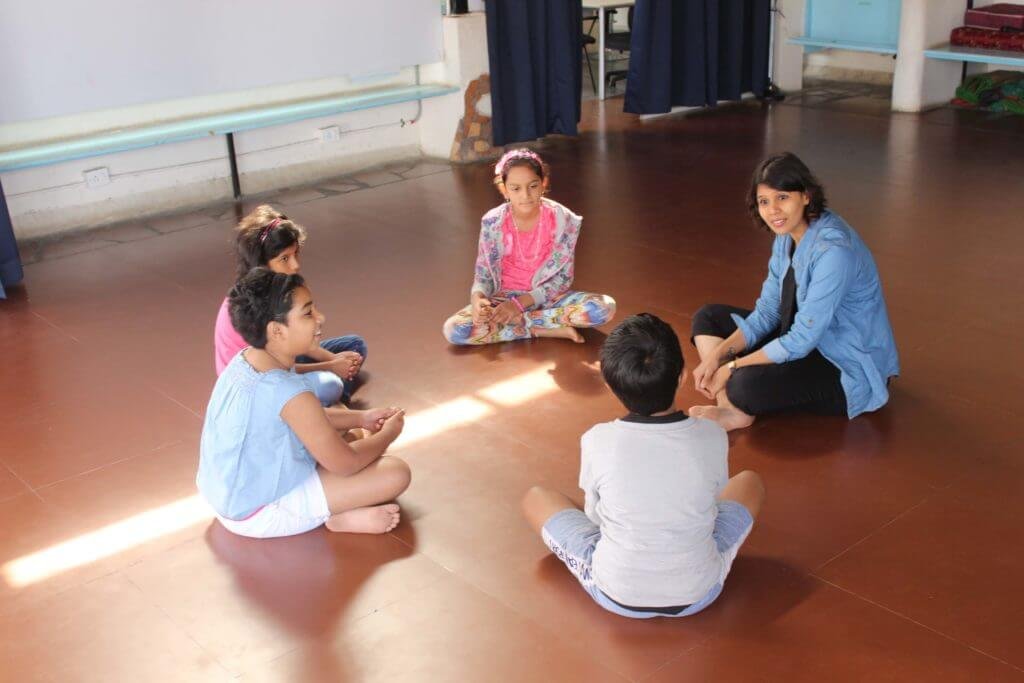 Children sitting on a studio floor with a facilitator