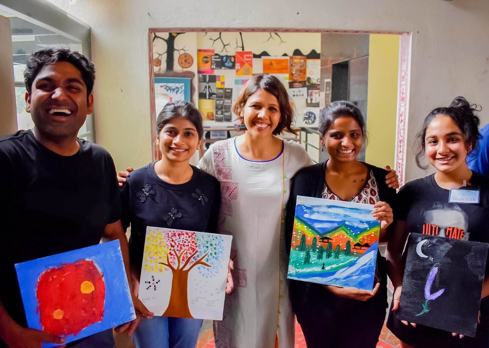 Workshop participants smiling and holding up their paintings